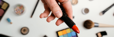Person holding lipstick over a table of makeup