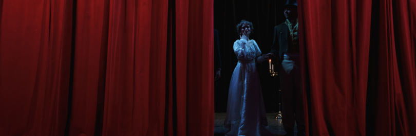 man-and-woman-standing-behind-a-red-curtain