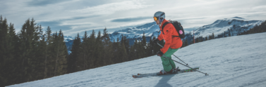 Person skiing downhill on snowy mountain during the day
