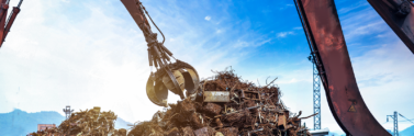 Large crane grabbing scrap metal from junk yard
