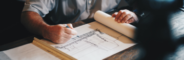 Person working on housing blueprint on table