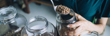 Person filling dried produce into a glass jar