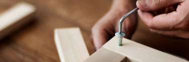 Person screwing in chair’s nail for ready-to-assemble furniture